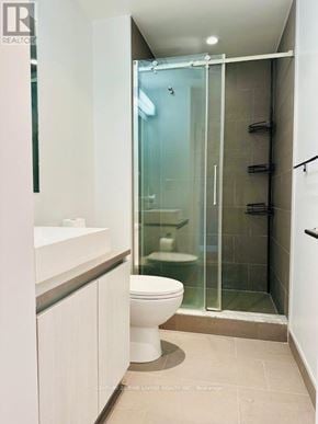 Toronto (Waterfront Communities) condo for rent - A white toilet in a small bathroom with a glass shower door.