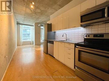Toronto (Little Portugal) condo for rent - A kitchen with white cabinets and black appliances.
