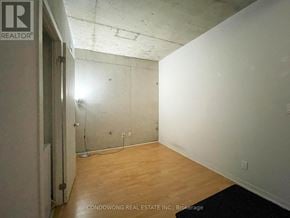 Toronto (Little Portugal) condo for rent - A room with a wooden floor and white walls, with a door on the left and a mat on the right.
