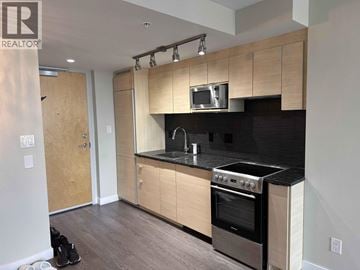 Vancouver apartment for rent - A kitchen with wooden cabinets and a black countertop.
