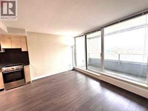 Vancouver apartment for rent - A spacious room with a stove and a large window overlooking a cityscape.