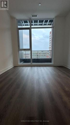 Markham (Unionville) condo for rent - A room with wooden floors and a large window overlooking a cityscape.