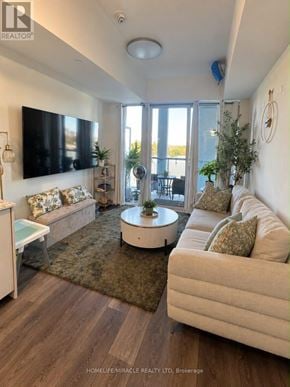 Toronto (Don Valley Village) condo for rent - A living room with a white couch, a coffee table, and a flat screen TV mounted on the wall.