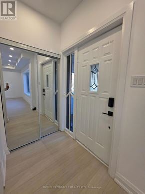 Toronto (Bendale) multi-family for rent - A white door with a glass panel and a black handle is in a room with wooden flooring.