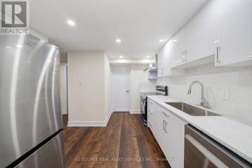 St. Catharines (Carlton/Bunting) apartment for rent - A kitchen with a stainless steel refrigerator and wooden floors.