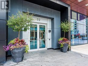 Toronto (Annex) condo for rent - The front of a building with the number 32 on it and two potted plants on the sidewalk.