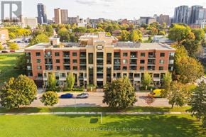 Ottawa condo for rent - A large apartment complex with a parking lot in front.