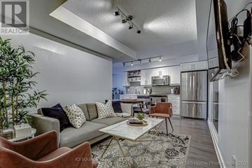Toronto (Waterfront Communities) condo for rent - A modern living room with a grey sofa, a coffee table, and a television mounted on the wall.