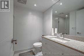 Toronto (Waterfront Communities) condo for rent - A white bathroom with a toilet, sink, and mirror.