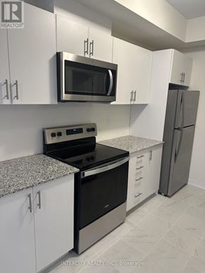 Toronto (Malvern) townhouse for rent - A kitchen with white cabinets and a black stove top oven.