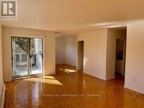 Mississauga (Cooksville) house for rent - A spacious room with a wooden floor and white walls, with a sliding glass door leading outside.