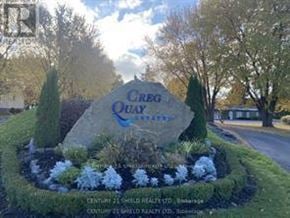 South Glengarry apartment for rent - A large rock with the words "Creg Quat" written on it is surrounded by bushes and trees.