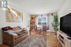 Ottawa condo for rent - A living room with a brown couch, a bookshelf, a television, and a potted plant.