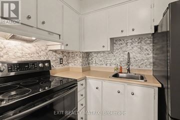 Ottawa condo for rent - A kitchen with a black stove top oven and white cabinets.