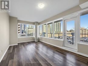 Toronto (Niagara) condo for rent - A room with wooden floors and large windows overlooking a cityscape.