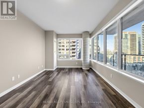 Toronto (Niagara) condo for rent - A spacious room with wood flooring and large windows overlooking a cityscape.
