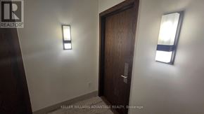Toronto (Regent Park) condo for rent - A hallway with a wooden door and two wall-mounted lights.