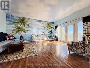 Fort Erie (Central) apartment for rent - A living room with wooden floors and a wall mural of a beach scene.
