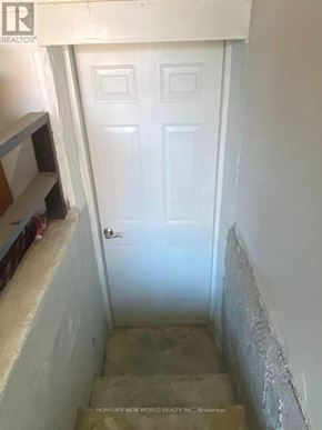 Vaughan (Glen Shields) apartment for rent - A white door in a narrow hallway with a sign that reads "HOMELIFE NEW WORLD REALTY INC. Brokerage".