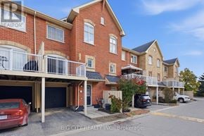 Pickering (Town Centre) townhouse for rent - A red car is parked in front of a brick building with a balcony.