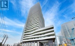 Pickering (Bay Ridges) condo for rent - A tall, modern building with a curved facade is under construction with a crane visible in the background.