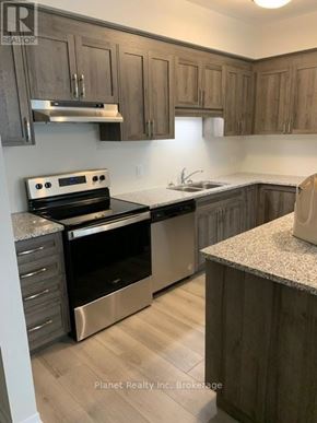 Kitchener townhouse for rent - A kitchen with wooden cabinets and a stainless steel oven.