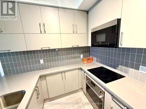 Markham (Unionville) condo for rent - A kitchen with white cabinets and a black microwave above the stove.
