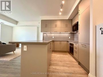 Markham (Unionville) condo for rent - A living room with a grey sofa and a table with a fan on the ceiling.