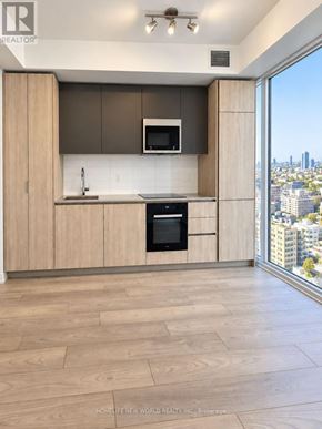 Toronto (Waterfront Communities) condo for rent - A modern kitchen with wooden cabinets and a city view.