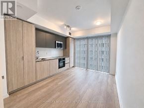 Toronto (Waterfront Communities) condo for rent - A well-lit kitchen with wooden cabinets and a microwave above the stove.