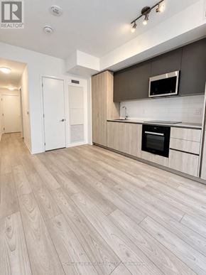 Toronto (Waterfront Communities) condo for rent - A modern kitchen with a wooden floor and white walls.