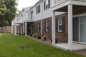 Cedarburg apartment for rent - a view of the exterior of an apartment building with a lawn and a porch