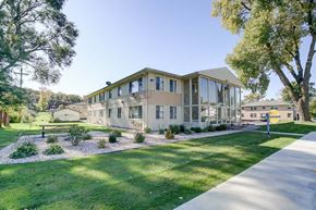 Monona apartment for rent - a building with a lawn and trees in front of it