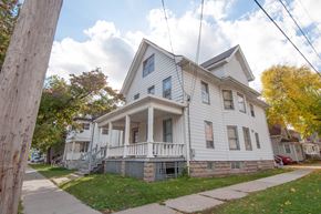 Madison triplex for rent - a white house with a porch and a sidewalk