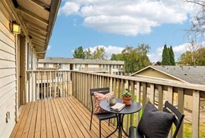 Fife apartment for rent - A wooden deck with a table and chairs overlooking apartment buildings.