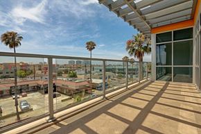 Culver City apartment for rent - A balcony with a metal railing and palm trees in the background.
