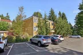 Bellevue apartment for rent - A parking lot with cars and a yellow building in the background.