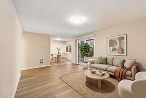 Bellevue apartment for rent - Living room with a sofa, a round coffee table, a sliding glass door to a patio, and a dining area beyond.