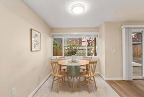 Bellevue apartment for rent - Dining area with a round table and four chairs, a window, and a sliding door with vertical blinds to a patio.