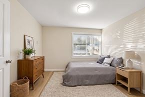 Bellevue apartment for rent - Bedroom with a queen bed, a wood-tone dresser, a nightstand, and a window with blinds on plank-style flooring.