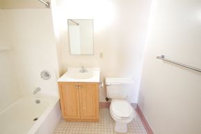 Newark apartment for rent - bathroom with light wooden cabinet, white tile floor and white walls