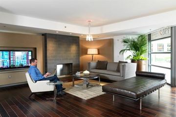 Washington apartment for rent - A man in a blue shirt is sitting on a white chair in a modern living room.