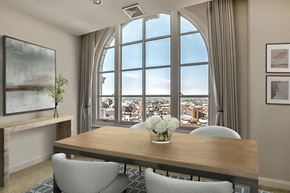 Baltimore apartment for rent - A dining room with a wooden table and chairs, a vase with white flowers, and a large window with a view of the city.