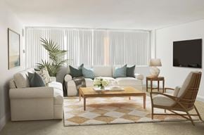 Baltimore apartment for rent - A living room with a white couch, a wooden coffee table, and a TV on the wall.