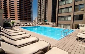 Baltimore apartment for rent - A pool surrounded by lounge chairs in a city setting.