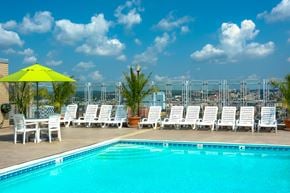 Baltimore apartment for rent - the pool on the rooftop of a hotel with white chairs and a yellow umbrella