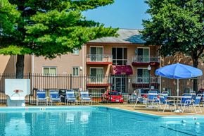 Oxon Hill apartment for rent - a swimming pool with chairs and a building in the background