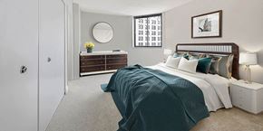 Baltimore apartment for rent - A bedroom with a bed, nightstand, and a dresser with a mirror.