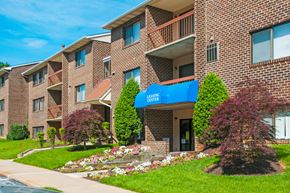 Baltimore apartment for rent - a brick apartment building with a blue awning and flower gardens