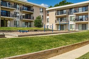 Beltsville apartment for rent - a playground in front of an apartment building with a blue bench